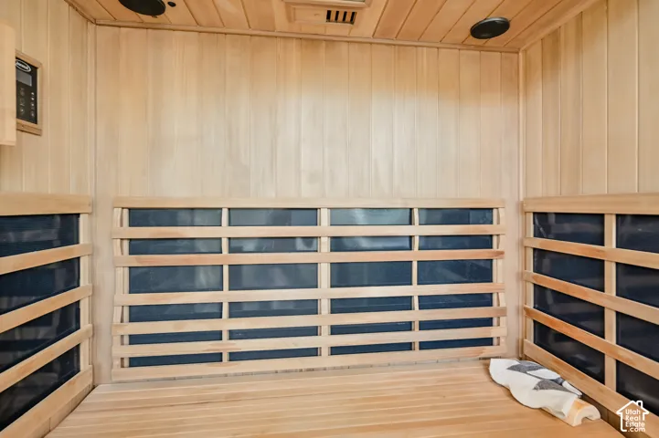 Dedicated sauna room featuring light-toned wood paneling, slatted wood benches, and integrated control panel