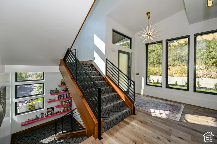 Foyer featuring a modern staircase with wood-finish treads and metal railings, large floor-to-ceiling windows, and wood-finish flooring