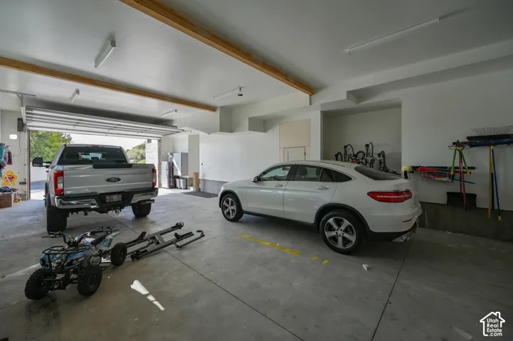 Spacious garage featuring a concrete floor, overhead lighting, and exposed wood ceiling beams