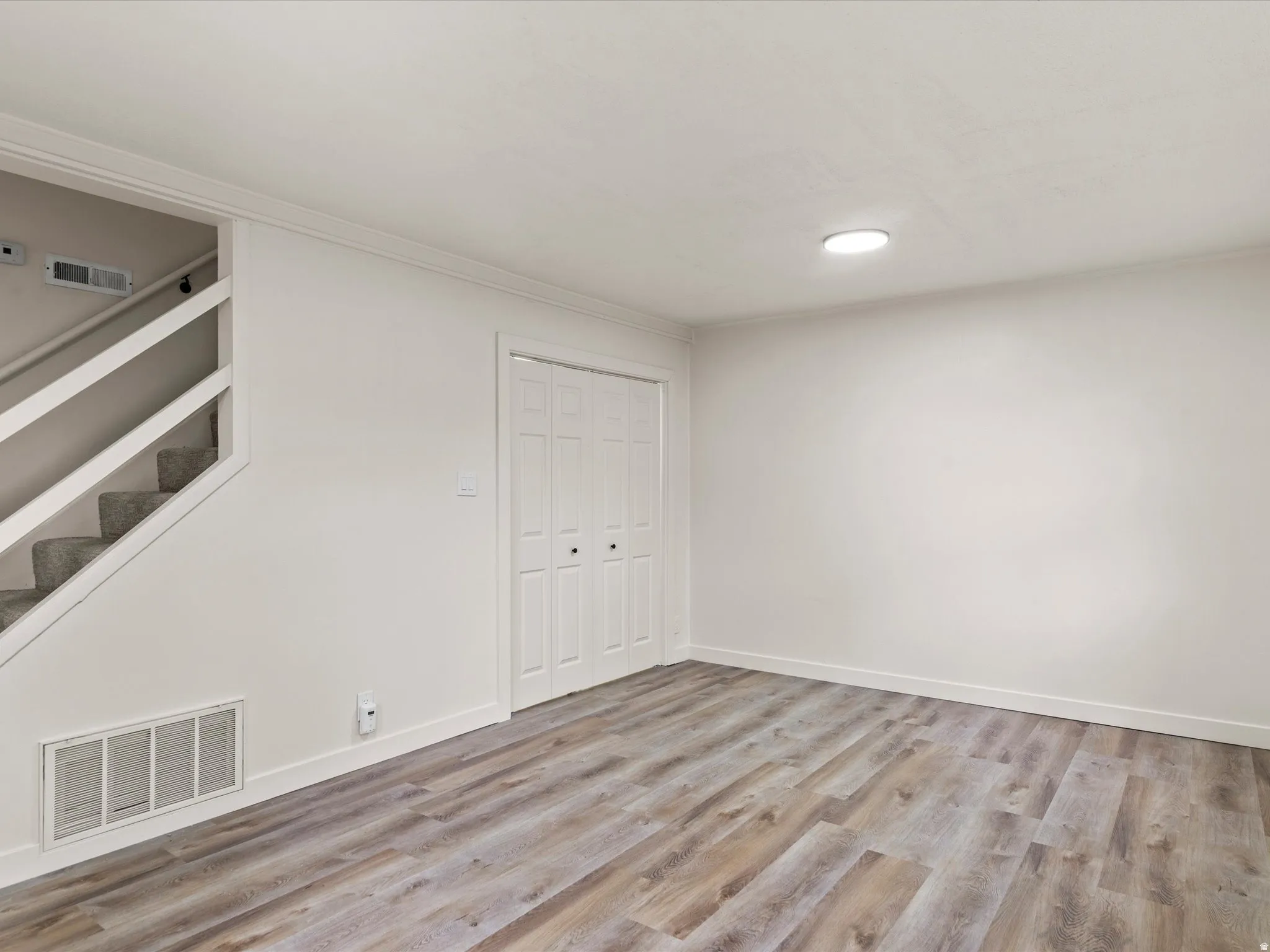 Interior space featuring wood-finish flooring, white walls, and bright overhead lighting