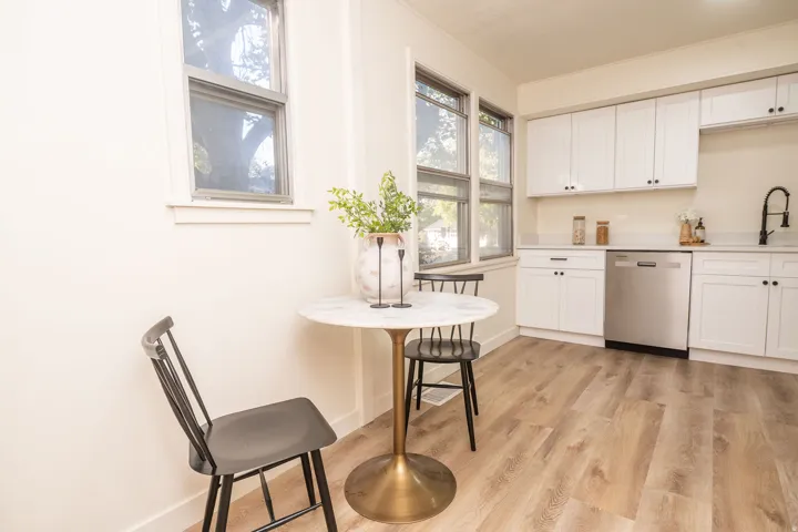 Bright kitchen space featuring white cabinetry, light countertops, wood-finish flooring, a stainless steel dishwasher, and a black faucet