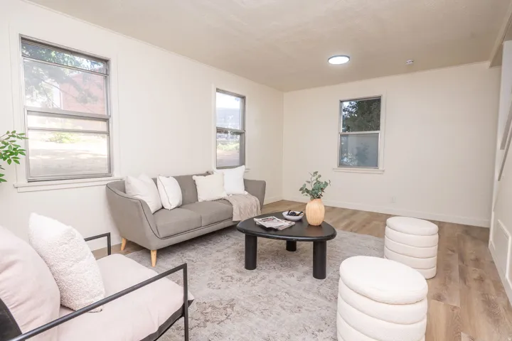 Bright living area featuring light-toned walls, wood-finish flooring, and multiple windows