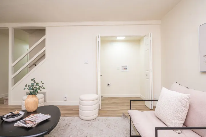Modern living space featuring clean white walls, warm wood-finish flooring, and abundant natural light
