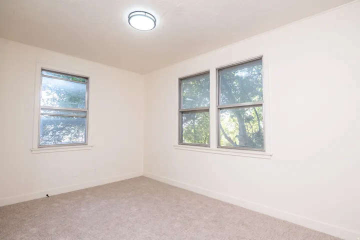 Bright corner bedroom bathed in natural light from two multi-pane windows