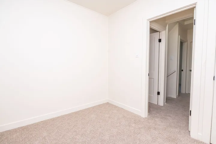 Spacious bedroom featuring neutral wall finishes, neutral-toned carpet flooring, and direct access to a hallway with multiple closet storage options and additional room entries