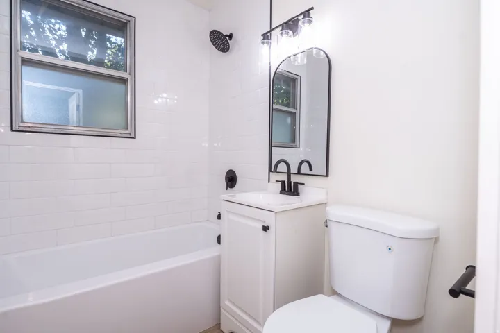 Bathroom featuring a white subway tile surround, white bathtub, and a window with frosted lower pane