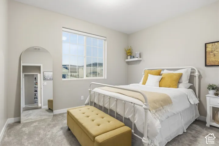 Bedroom with expansive window, neutral wall tones, and plush carpet flooring
