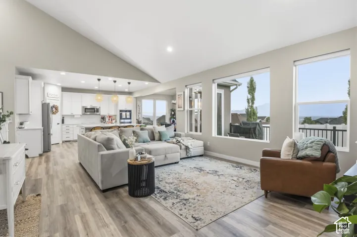 Open-concept living space featuring a vaulted ceiling and wood-finish flooring