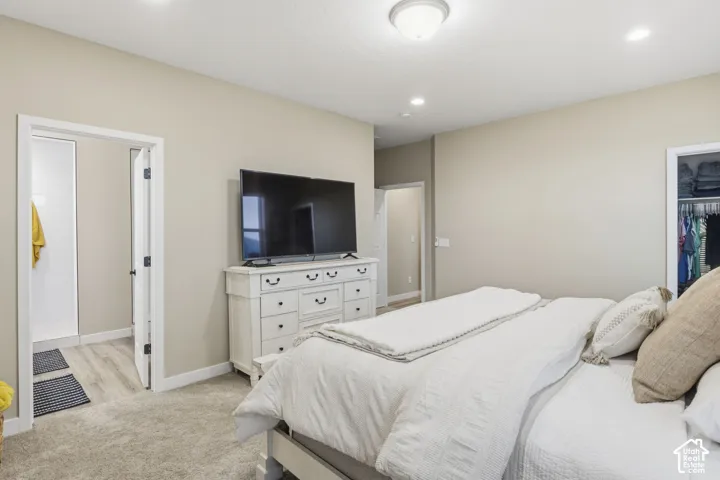 Carpeted bedroom featuring neutral wall tones, recessed lighting, and a ceiling-mounted light fixture