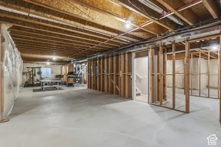 Unfinished basement offering substantial square footage, exposed wood framing, concrete flooring, and a visible staircase providing access to the upper level