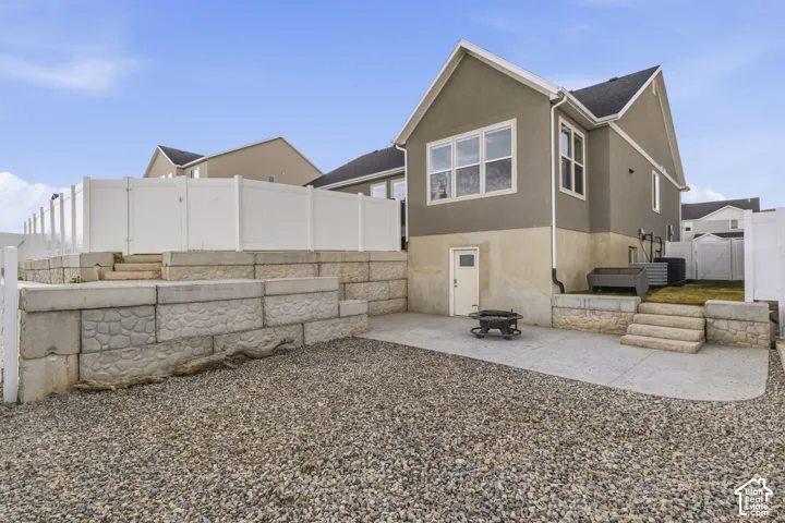 Rear exterior featuring a stucco finish, multiple windows, and a lower-level access door