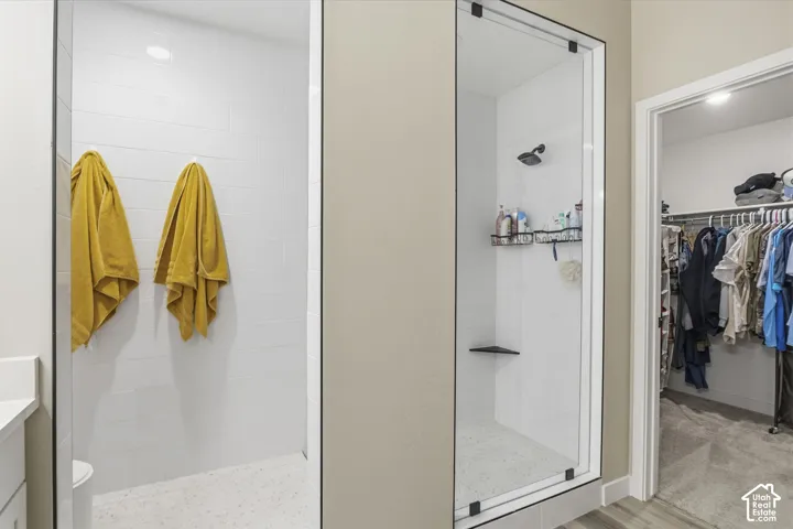 Walk-in shower with clear glass enclosure and black trim, featuring white subway tile walls and a built-in corner shelf