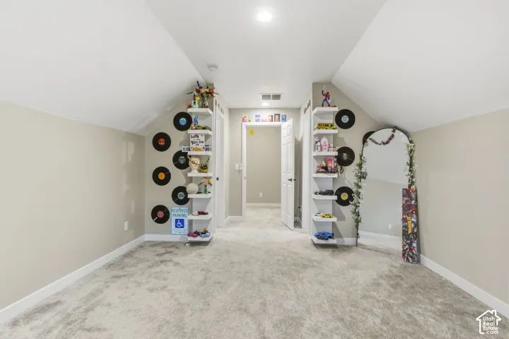 Carpeted upper-level room with sloped ceilings