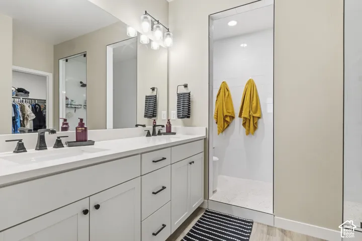 Bathroom featuring a dual vanity with white cabinetry, white countertops, and matte black hardware
