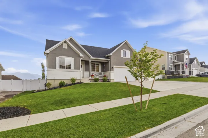 Contemporary stucco exterior featuring a covered front porch, white window shutters, and an attached garage
