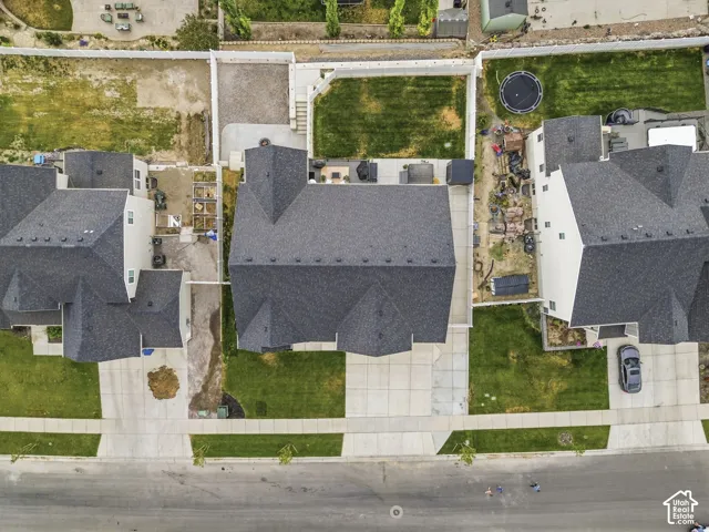 Property featuring a dark shingle roof, concrete driveway, and established front lawn