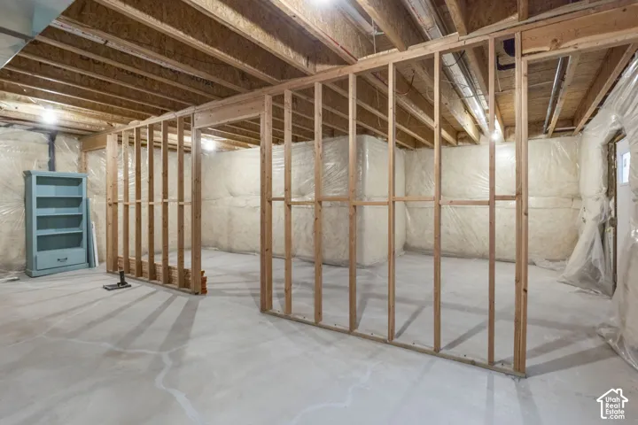 Unfinished basement featuring exposed wood framing, concrete flooring, and ceiling joists
