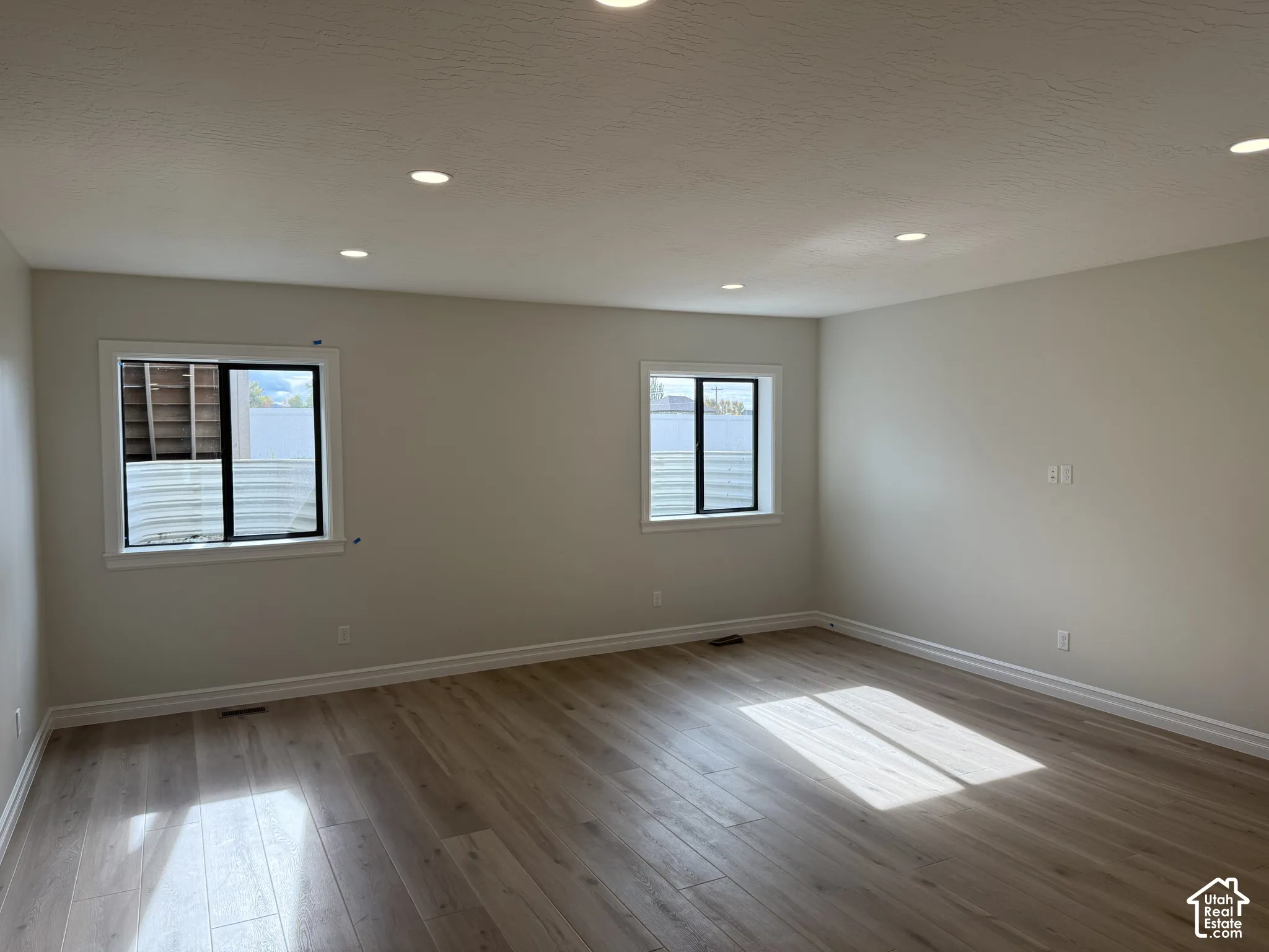 Neutral interior featuring wood-finish flooring, recessed lighting, and two windows with black frames