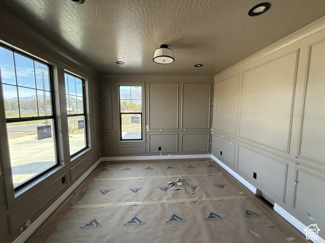 Walls featuring panel molding, multiple windows with dark frames, recessed ceiling lighting, and a central ceiling light fixture
