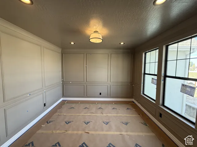 Wainscoting wall trim, multiple windows with dark frames, recessed lighting, and a central ceiling fixture