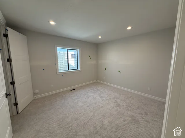 Recessed ceiling lighting, light-colored carpeting, white trim, and a window with a window well