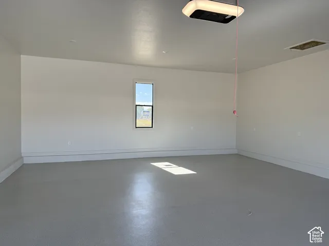 Spacious interior with painted walls, a single pane window, and a built-in garage door opener