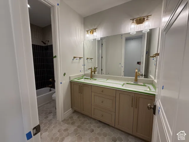 Dual vanity with wood-finish cabinetry, light-toned countertop, and gold-finish fixtures