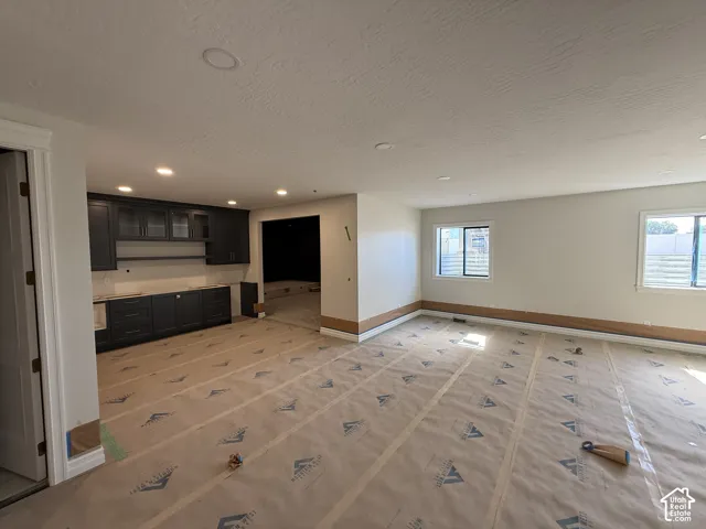 Recessed ceiling lighting, dark cabinetry with upper glass-front cabinets, white subway tile backsplash, and multiple windows