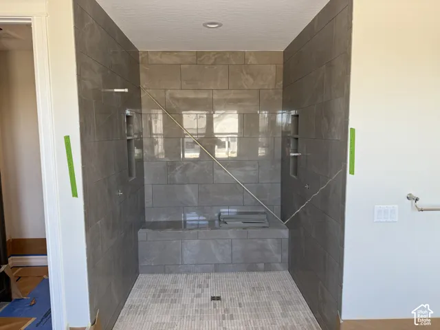 Walk-in shower with large format wall tiles, built-in bench, and dual recessed niches