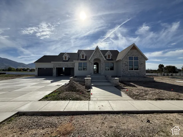 Stone and stucco exterior featuring a multi-gable roofline, dormer windows, and an arched entry