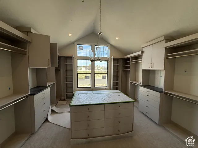 Vaulted ceiling, central island with drawers, integrated shelving, hanging rods, and transom windows
