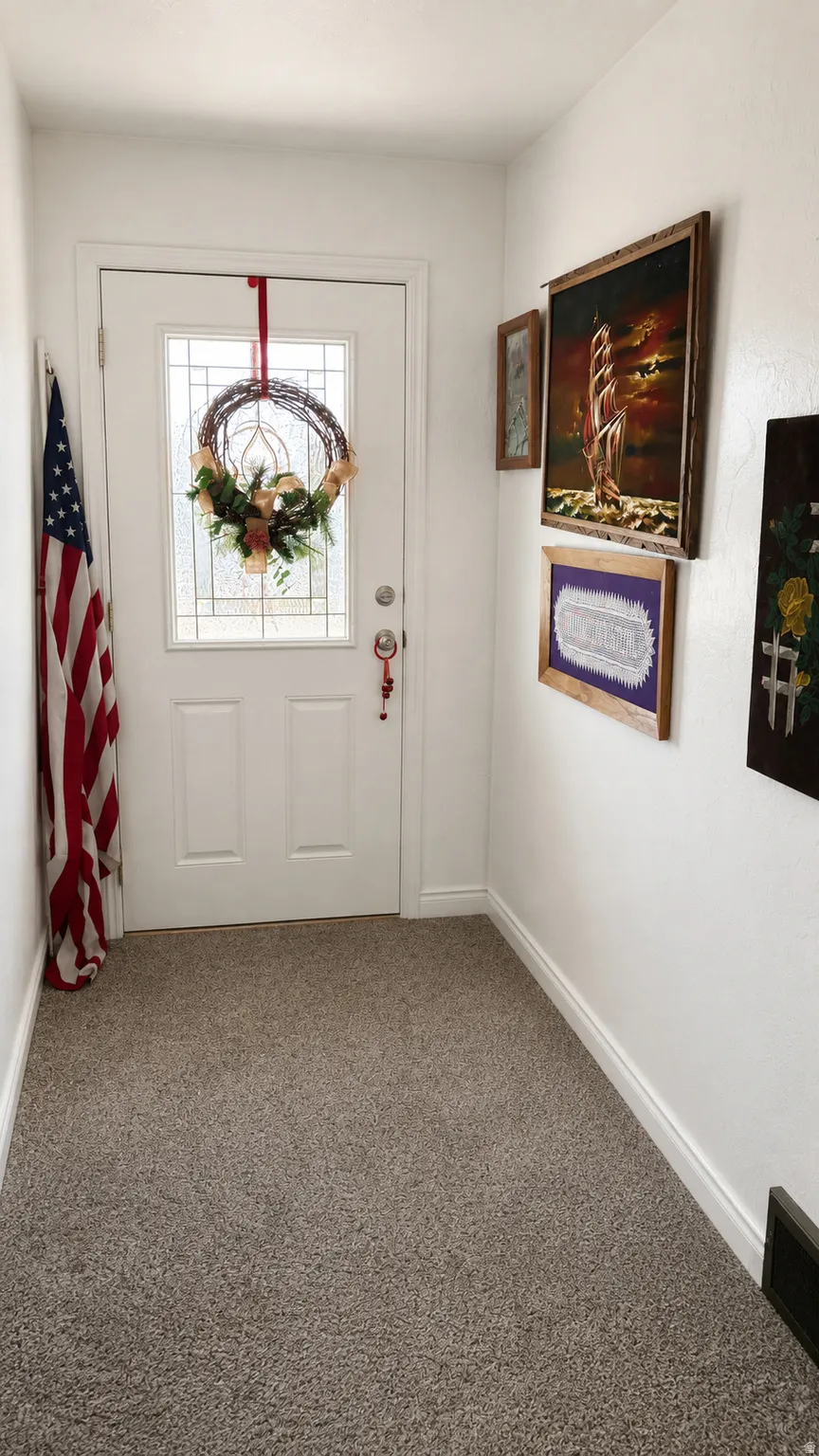 Entryway featuring a white door with a clear glass insert, light gray carpeting, white baseboards, and white wall finishes