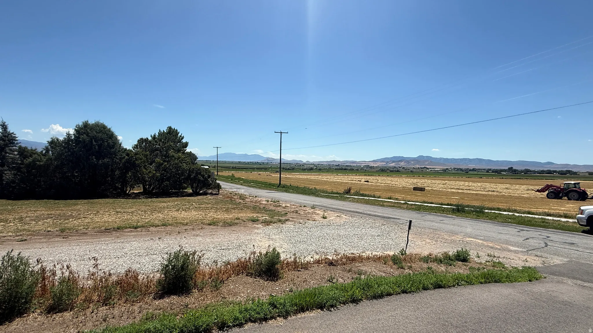 Expansive agricultural surroundings featuring a clear sky, distant mountains, and open fields