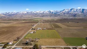 Expansive land featuring agricultural fields, scattered structures, and a clear mountain range backdrop