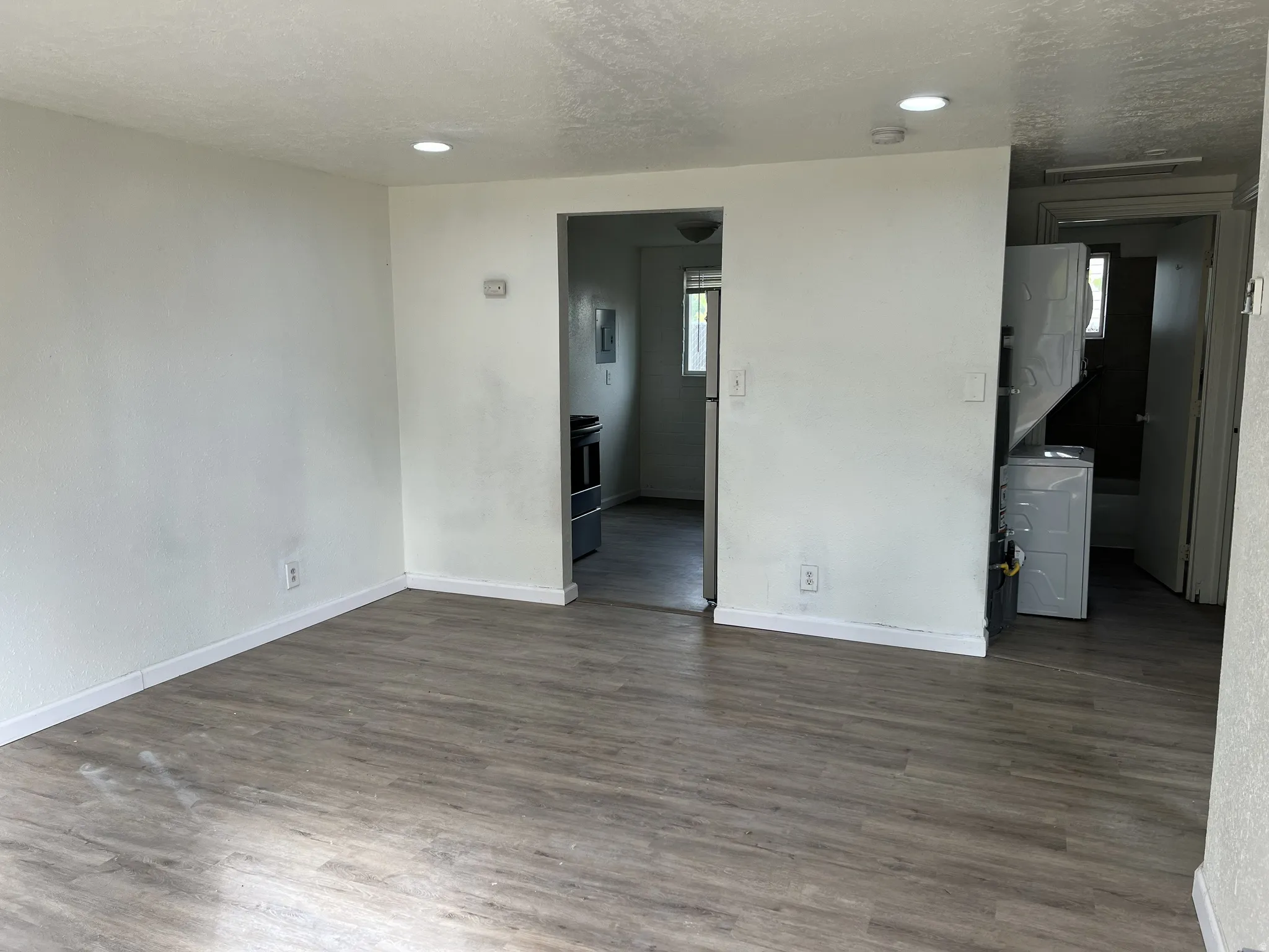 Spacious open area featuring wood-finish flooring, recessed lighting, and white baseboards