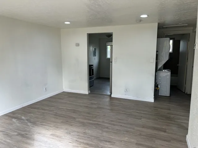 Spacious open area featuring wood-finish flooring, recessed lighting, and white baseboards