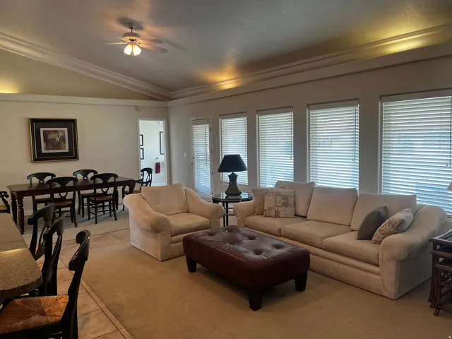 Spacious living area featuring neutral carpeting and a tray ceiling with crown molding