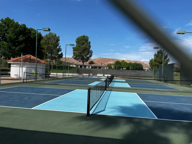 Multiple pickleball courts featuring blue and light blue playing surfaces with white boundary lines