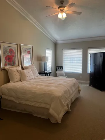 Vaulted ceiling featuring crown molding and a ceiling fan with integrated lighting