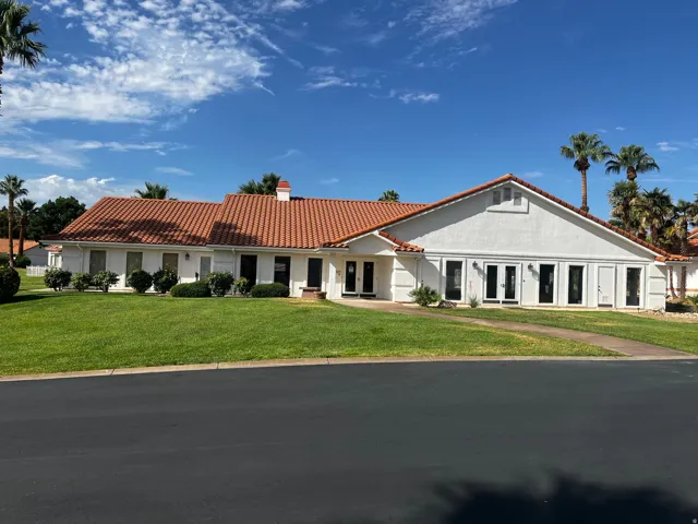 Mediterranean-style exterior featuring a red tile roof, white stucco facade, multiple windows, and a manicured front lawn