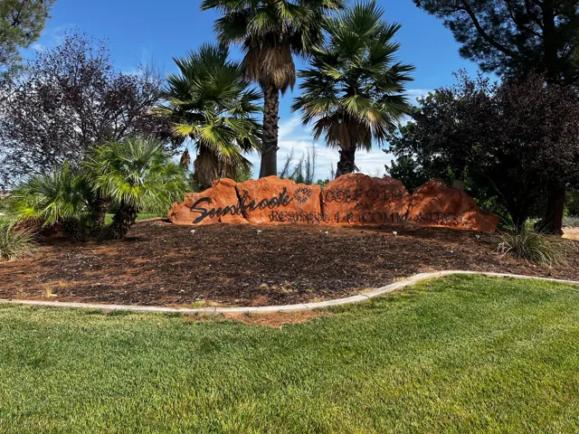 Stone monument signage surrounded by mature landscaping and a well-kept lawn