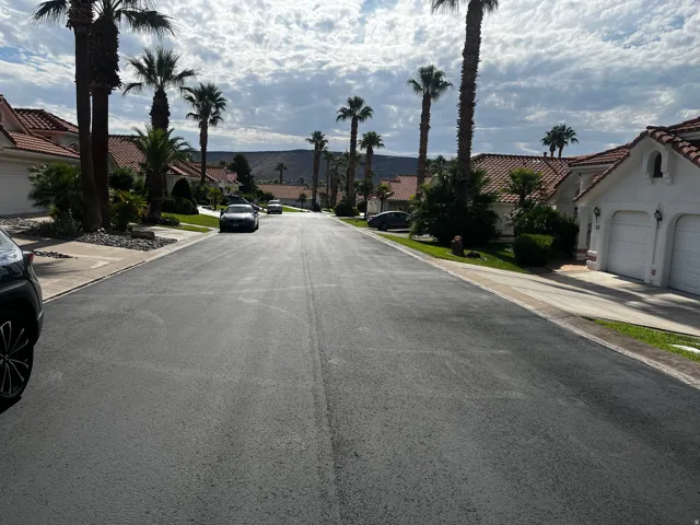Residential street with mature palm trees and Spanish-style homes featuring white stucco exteriors and terracotta tile roofs