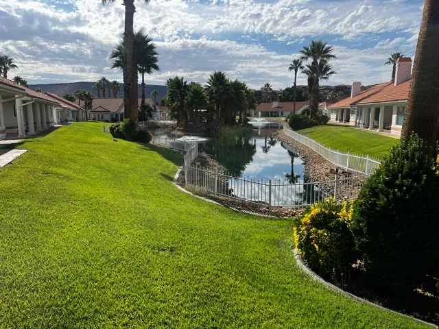 Expansive green lawn bordering a reflective pond with a fountain