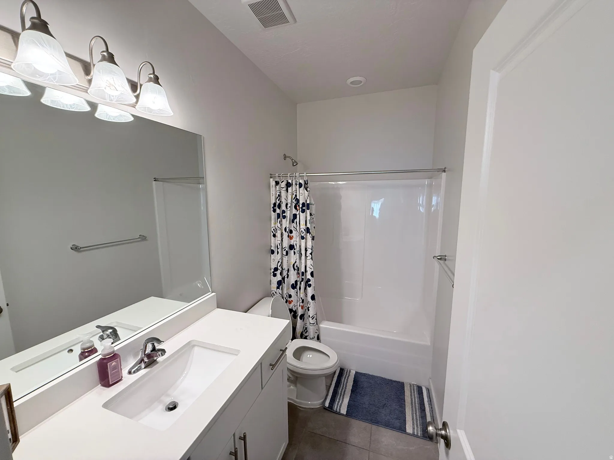 Bathroom featuring a white vanity with an integrated sink, polished chrome faucet, and a large wall-mounted mirror