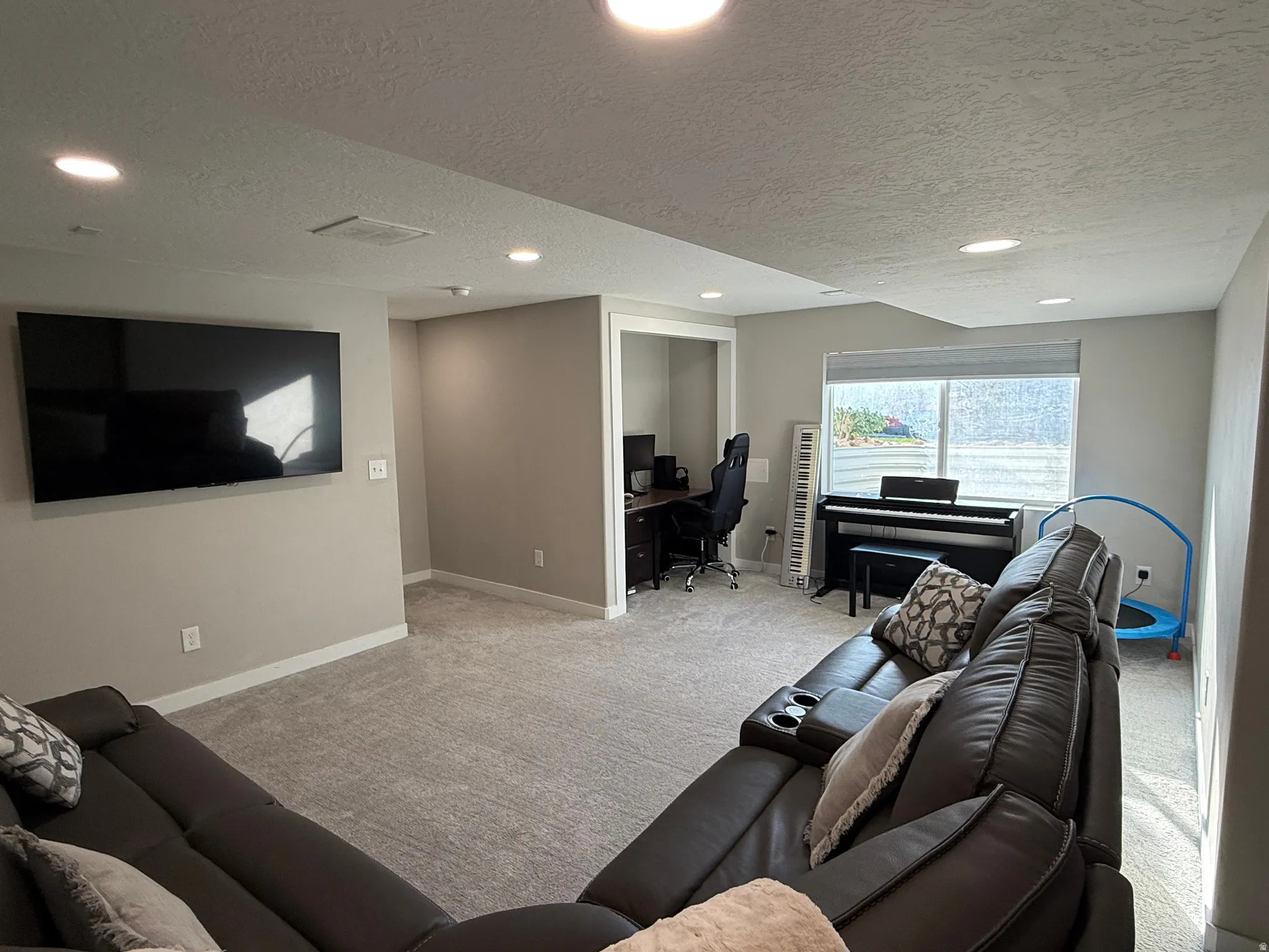 Spacious lower-level area featuring recessed lighting, light gray carpeting, and a large window providing ample natural light