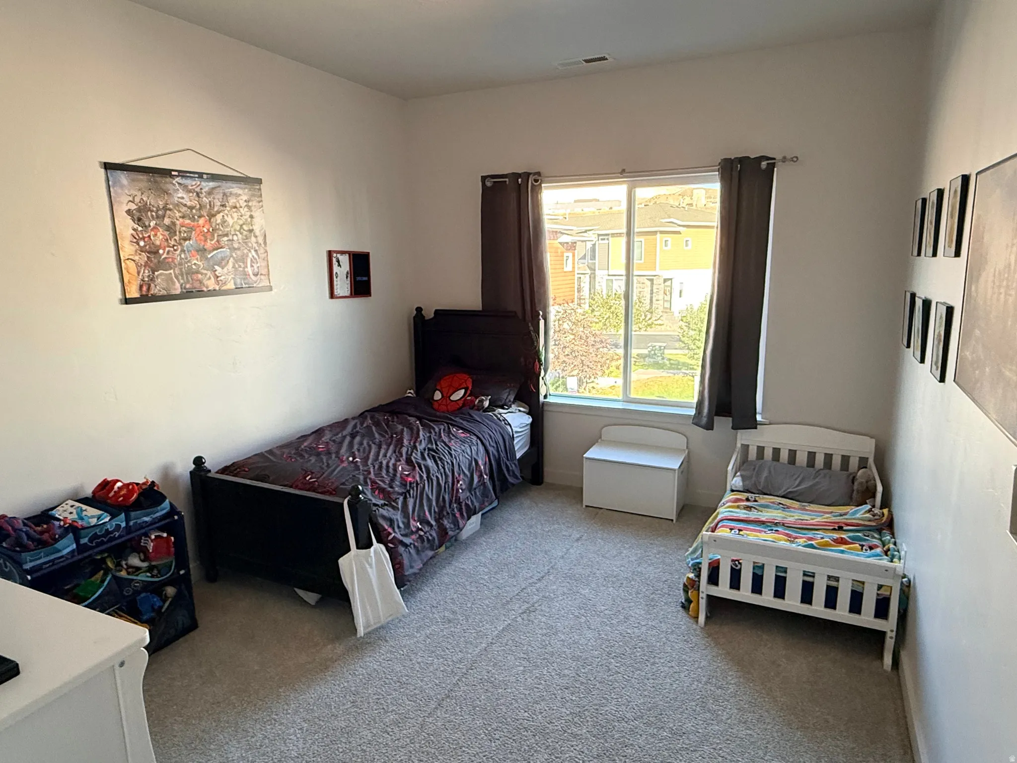 Light-filled room featuring a large window with exterior views, neutral wall tones, and textured carpeting