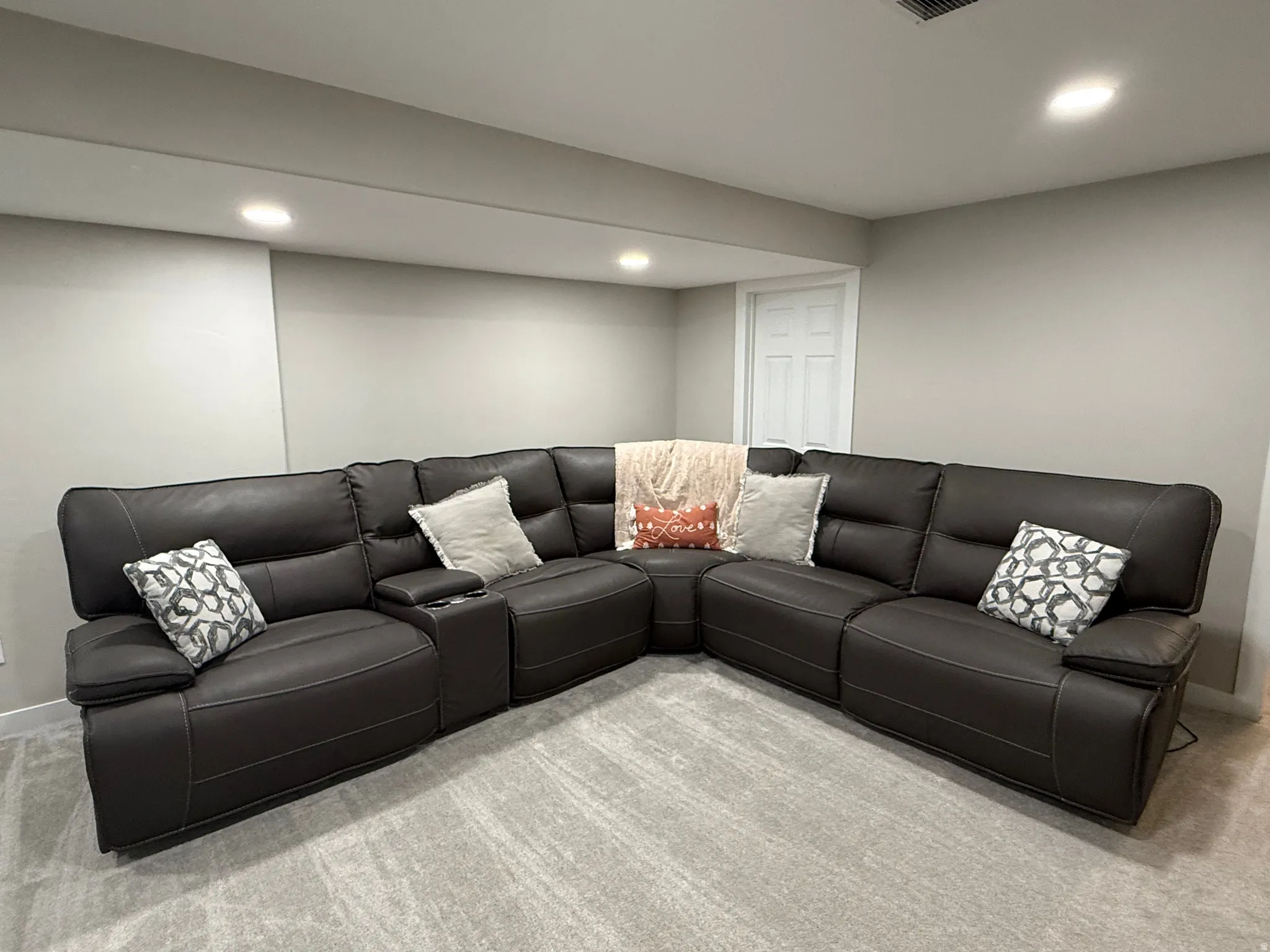 Recessed lighting illuminates the neutral wall colors and gray carpet flooring