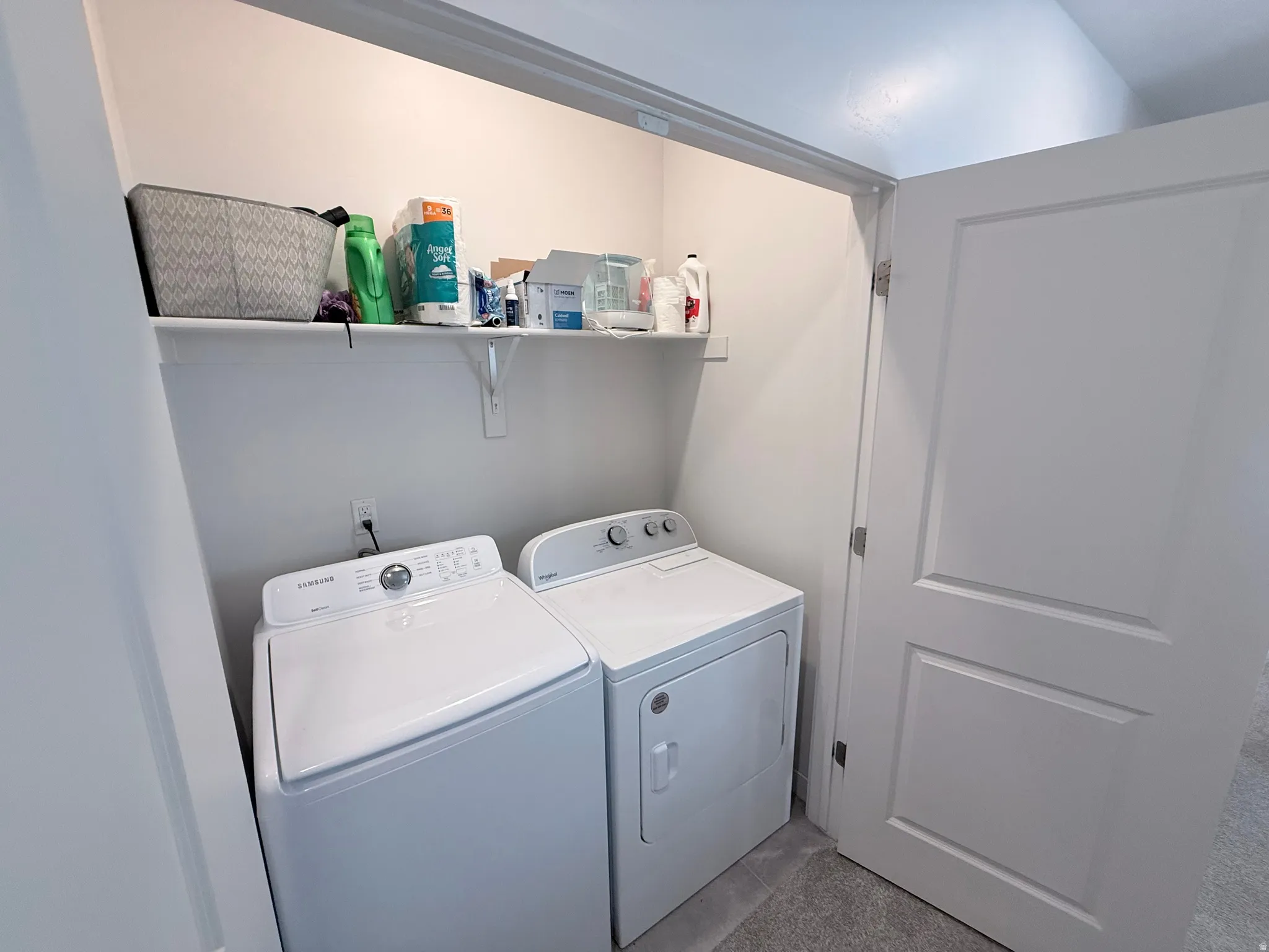 Dedicated laundry area featuring a built-in shelf, white walls, and a light-colored floor