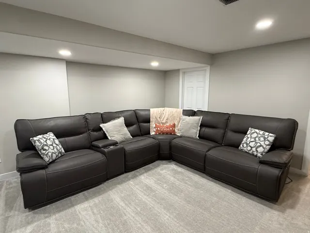 Recessed lighting illuminates the neutral wall colors and gray carpet flooring