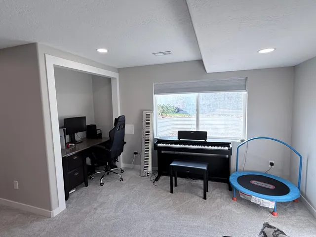 Recessed ceiling lighting illuminates a dedicated workspace nook, featuring a built-in desk with dark wood-finish cabinetry